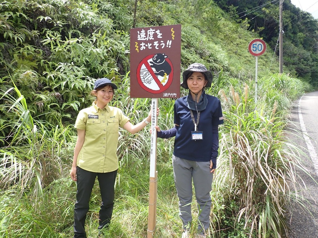 奄美野生生物保護センター提供：交通事故防止を呼び掛ける看板を設置した関係者ら＝１８日、瀬戸内町