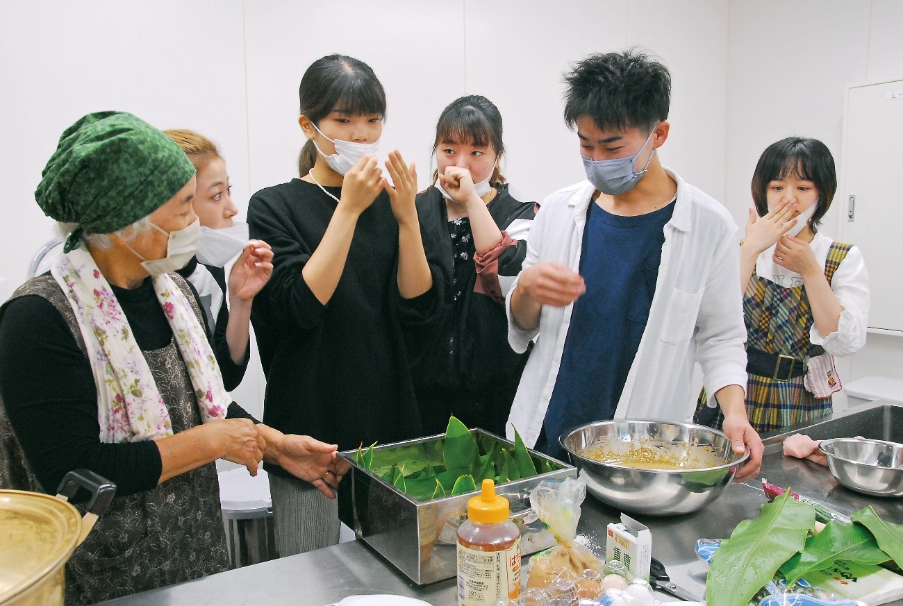 郷土料理作りに取り組むモニターツアーの大学生＝６日、龍郷町